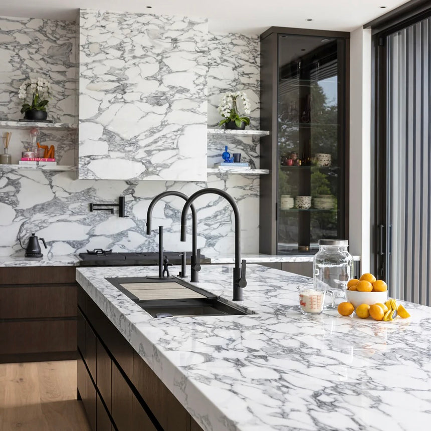 Modern kitchen with marble countertop, sink, and backsplash.