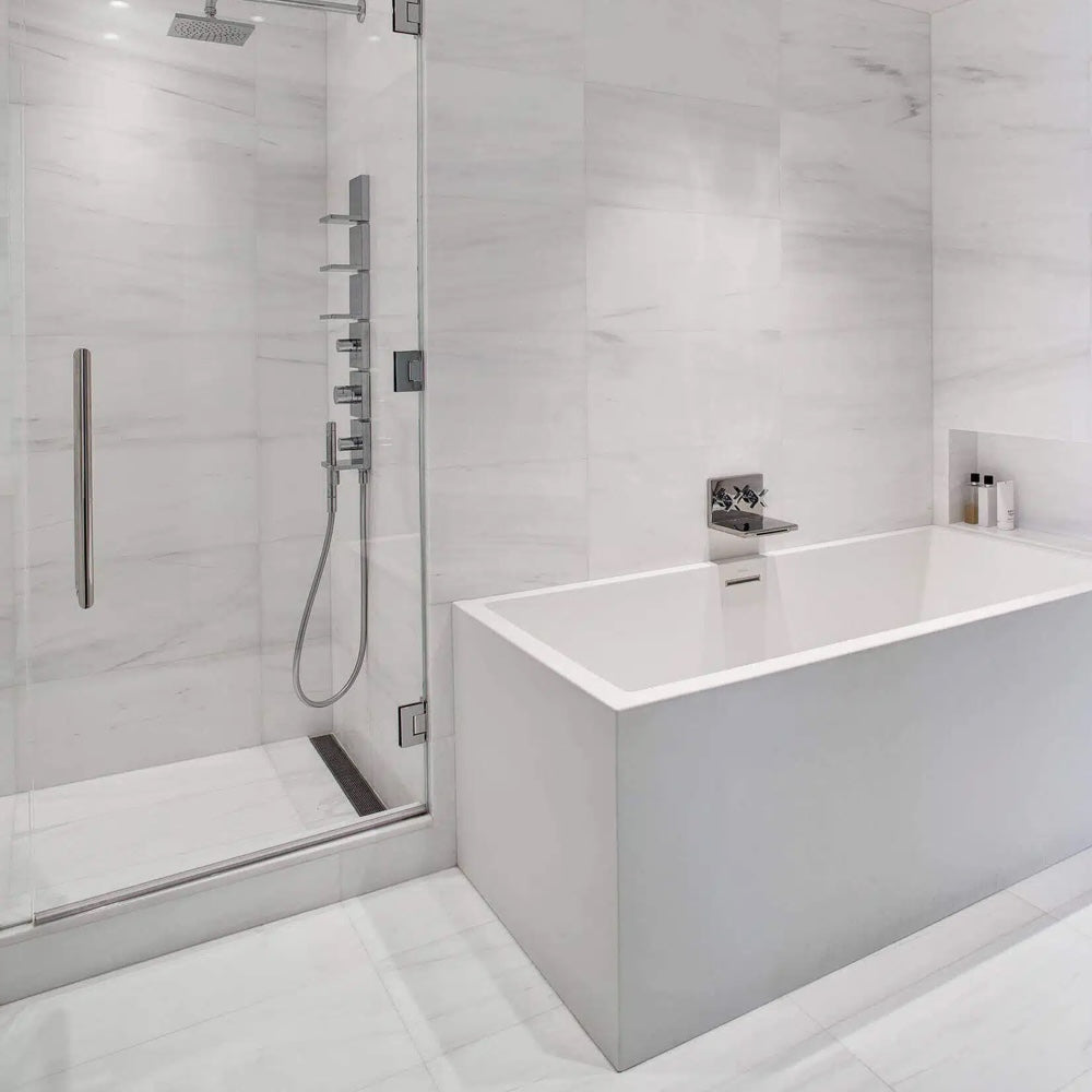 Modern bathroom with a white bathtub and glass shower enclosure.